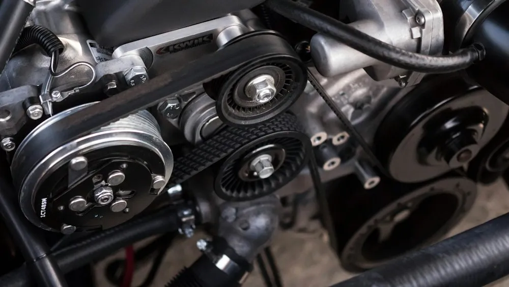 A close-up of engine belts, pulleys, and mechanical components