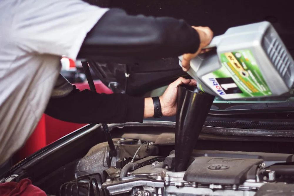 Motor oil being poured through a funnel into a vehicle's engine